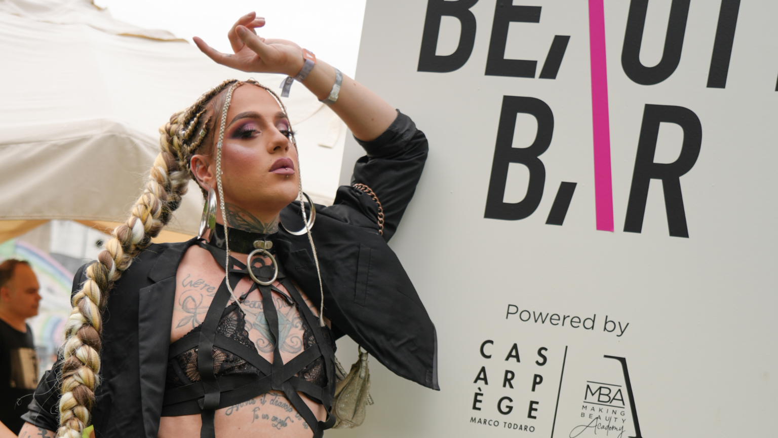 Una donna, con un look colorato e accattivante, posa sorridente davanti al palco principale del Kappa FuturFestival il festival dove nascono le nuove tendenze della bellezza.