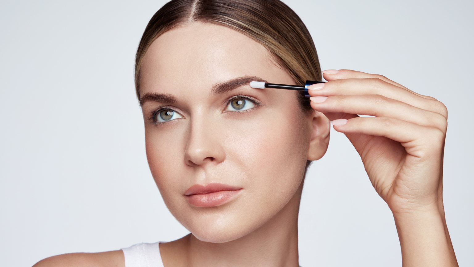 in foto, una ragazza su sfondo bianco che utilizza il siero per sopracciglia di revitalash cosmetics