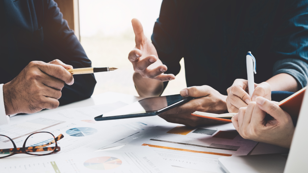 in foto è rappresentata una scrivania con dei fogli business e delle mani che gesticolano. Sta a significare la formazione e consulenza per il settore estetico, dell'azienda Beauty Training.