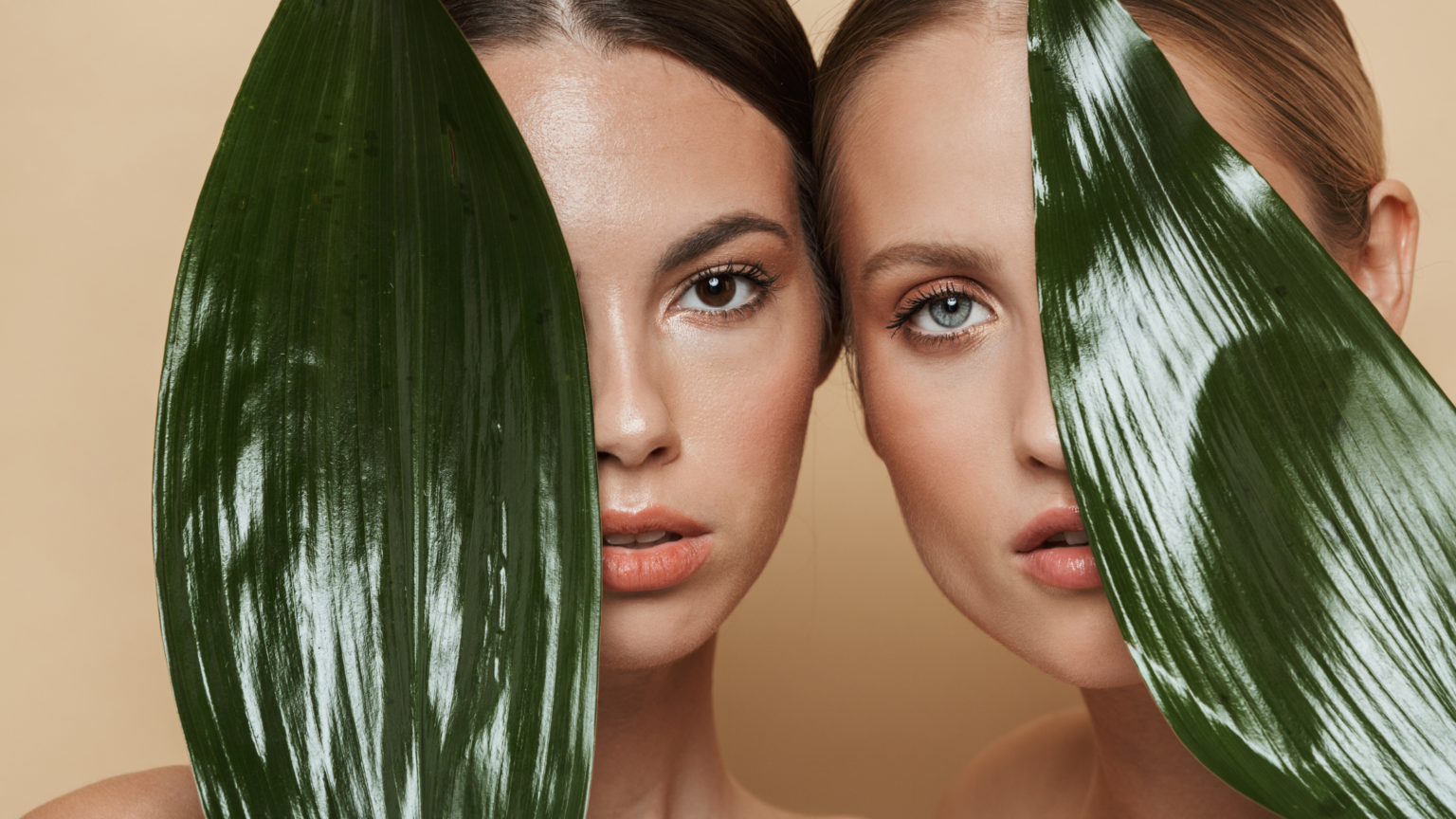 in foto, due donne su sfondo beige che coprono il viso con due foglie. rappresenta l'articolo dedicato a Tirs, sulla loro tecnologia estertica ispirata alla natura.