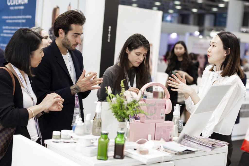 in foto delle persone che stanno guardando dei prodotti cosmetici con una consulente al cosmoprof 2025