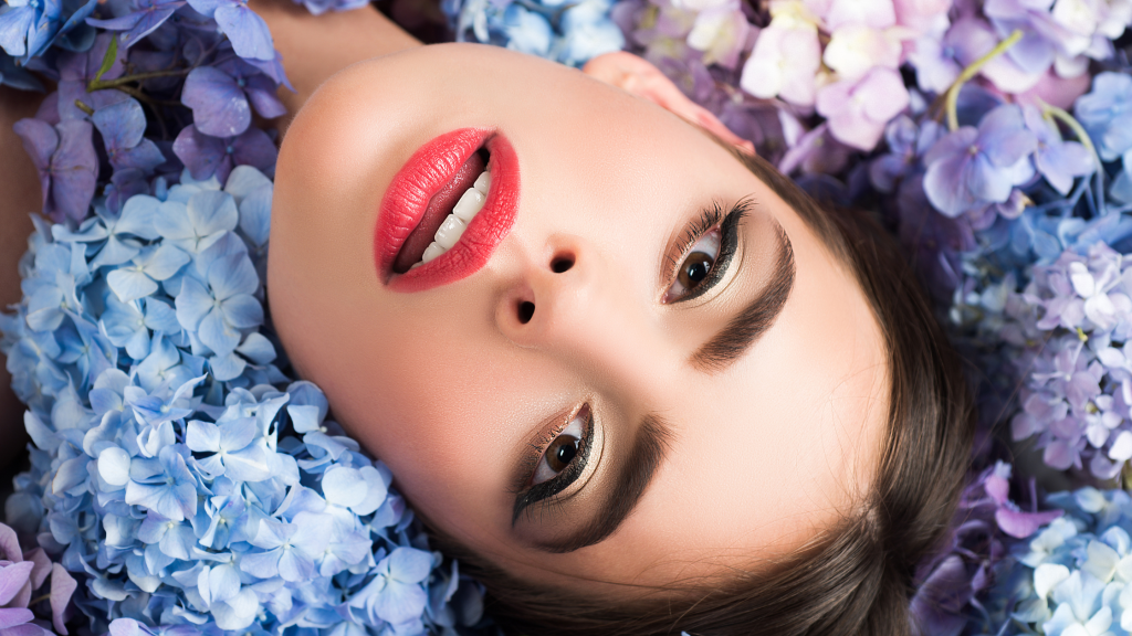 in foto un viso di donna con sotto dei fiori: rappresenta il tema dell'articolo, il beauty on demand.