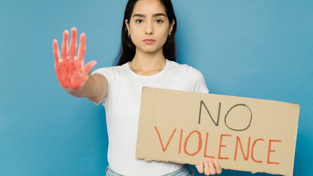 in foto una ragazza con un cartello contro la violenza sulle donne, in occasione del 25 novembre