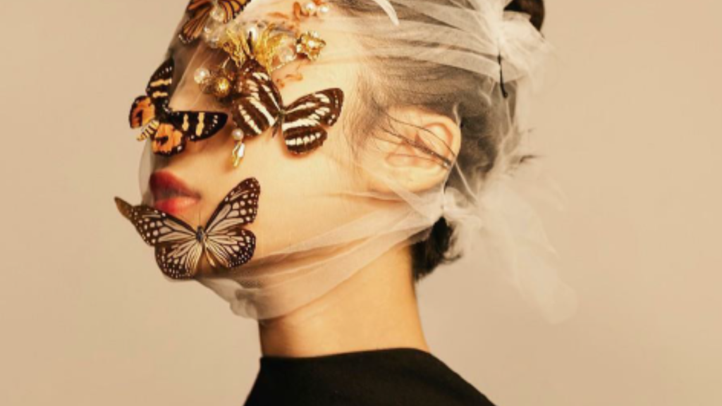 in foto una donna con delle farfalle sul viso. è l'immagine di copertina del convegno "la bellezza che fa bene" che racconta il ruolo sociale dell'estetista.