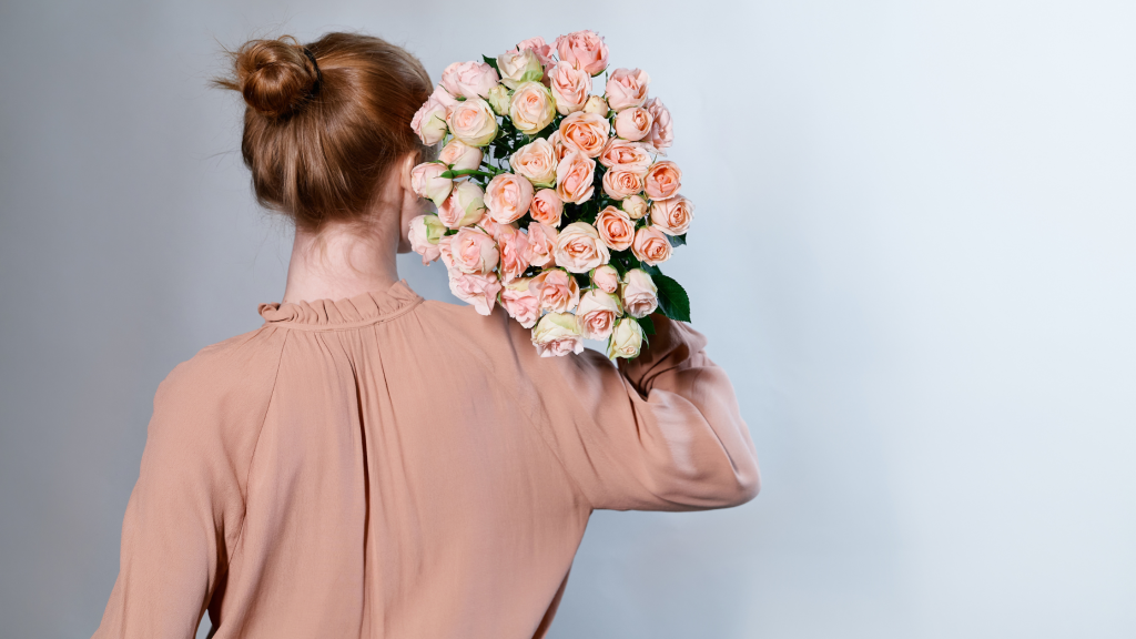 in foto una donna di spalle con dei fiori. rappresenta la festa della donna