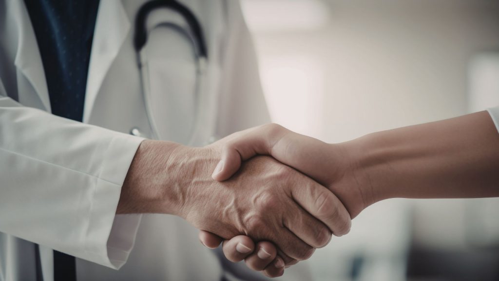 in foto due mani che si stringono. rappresenta la collaborazione tra estetista e chirurgo estetico